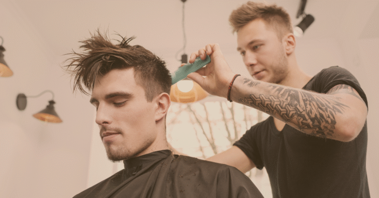 Barber styling a man’s hair with a comb in a modern salon, representing men’s grooming and haircare confidence