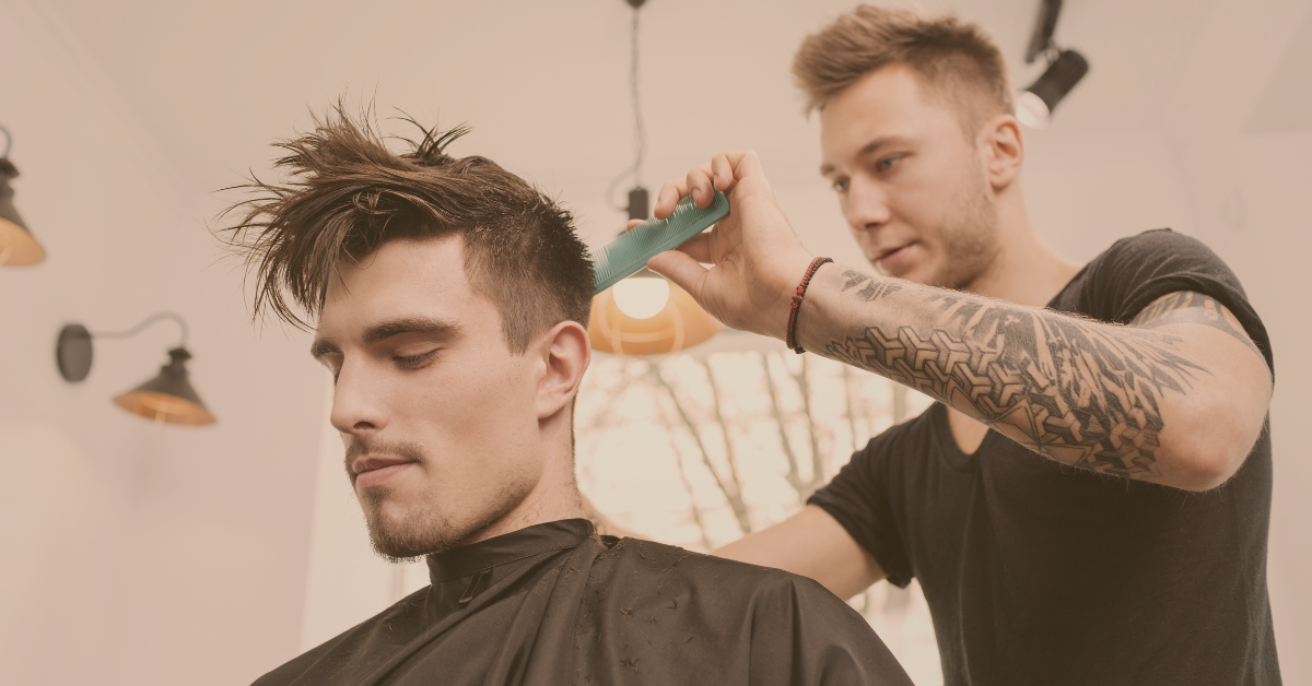 Barber styling a man’s hair with a comb in a modern salon, representing men’s grooming and haircare confidence